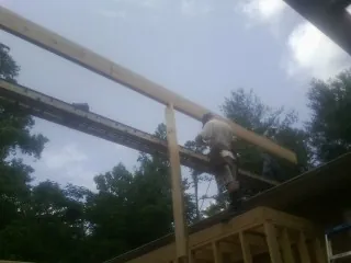 Carpenter setting a ridge beam over a new addition frame — Ice Dam Removal by Roofing Brothers in Saint Henry