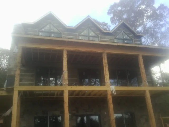 Dormers and porch framing on a large log home under construction — Roof Coating work by our crew in Saint Henry
