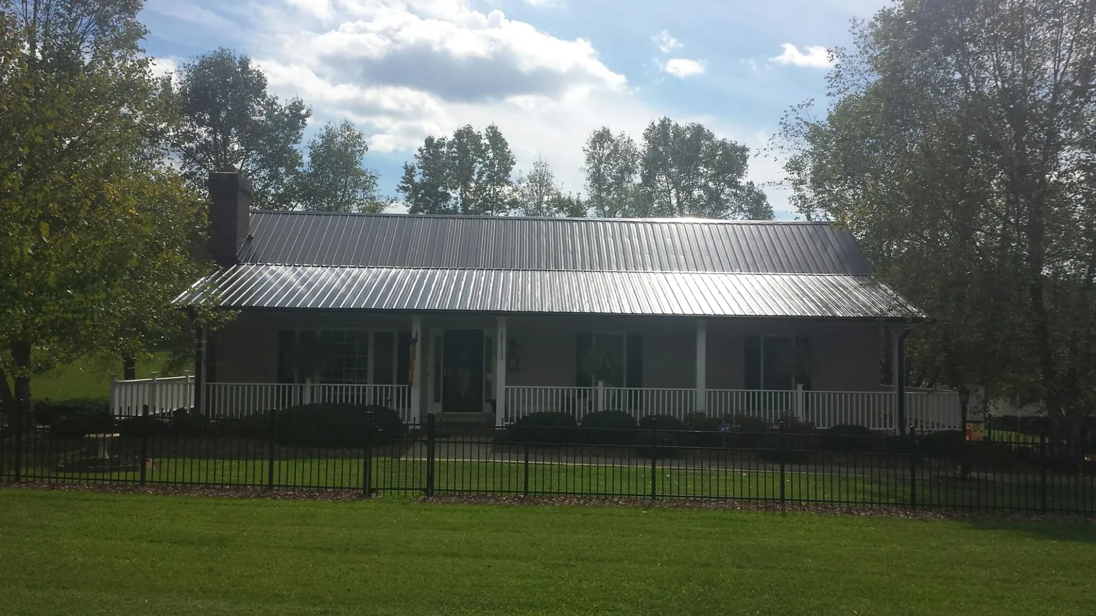 Gray metal roof on a brick ranch with a full width front porch — Gutter Guard Installation work by our crew in Saint Henry