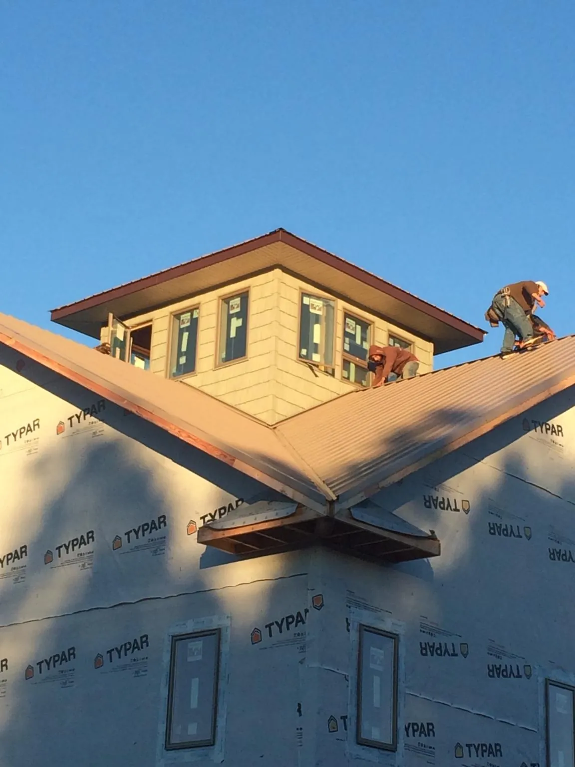 Roofers working around a rooftop cupola on a new metal roof at sunset — Roof Waterproofing in Saint Henry by Roofing Brothers